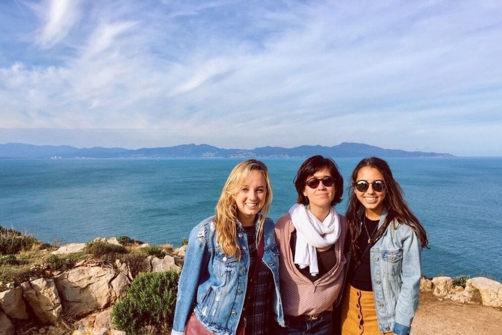 Three friends posing for a picture in front of the ocean 