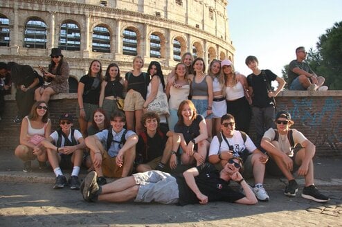 A group of teens pose in front of the Colosseum.